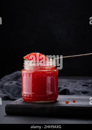 caviar rouge granuleux frais dans un pot en verre sur une table en bois Banque D'Images