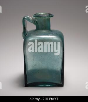 Flacon carré en verre 1st–3rd Century A.D. Roman bleu translucide, avec poignée de même couleur.rebord replié, au-dessus et à l'intérieur, formant une légère constriction à la bouche, avec surface supérieure biseautée; col cylindrique, avec repères d'outillage autour de la base; épaulement horizontal courbé avec coins arrondis et inclinés; côtés plats et verticaux; fond plat;Large poignée de sangle, avec décoration peignée sur la surface extérieure, fixée au bord extérieur de l'épaule, dressée verticalement, tournée en angle aigu et appliquée en pli épais au cou.décoration moulée sur le fond comprenant trois anneaux concentriques et point central en relief.C. Banque D'Images