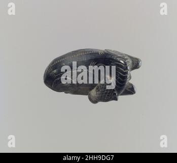 Inclinaison du mollet : fixation du couvercle env.9th–8th siècle av. J.-C. Assyrian cette petite figurine d'ivoire représentant un veau au repos a probablement été noircie par l'exposition au feu lorsque les complexes du palais à Nimrud ont été mis à pied pendant la défaite finale de l'Assyrie à la fin du septième siècle avant-C. le fond de la figurine est aplati et a été aplatiun trou rectangulaire, dans lequel une cheville pourrait être insérée comme moyen de fixer le mollet à un autre objet.Il était probablement fixé au couvercle d'une pyxis, une petite boîte ronde utilisée pour les biens précieux, y compris les produits de luxe tels que les épices, l'encens, les cosmétiques, le perfum Banque D'Images