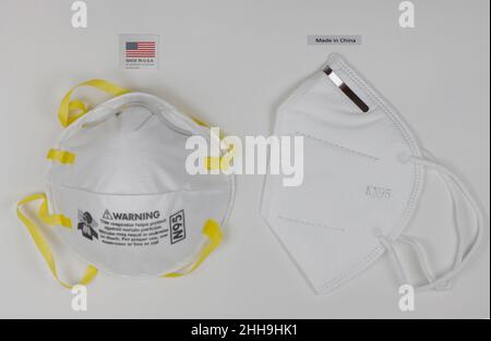 Masque respiratoire N95 fabriqué aux Etats-Unis à côté d'un masque facial KN95 fabriqué en Chine, avec des étiquettes ci-dessus, sur fond blanc Banque D'Images