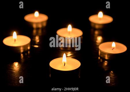 Bougies allumées sur une table sombre, fond noir, jour de la mémoire. Banque D'Images