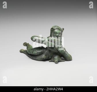 Statuette de bronze d'un satyr inclinable fin du 6th siècle avant-midi Etruscan cette charmante paire de satyres, l'un jouant les pipes Pan tout en s'inclinant sur un wineskin et l'autre tenant une corne de boisson, probablement une fois décoré le bord d'un grand navire de bronze.Ces dévotés de Dionysos, dieu du vin, sont des sujets appropriés sur un vase utilisé pour servir cette boisson.Leur style suggère un atelier dans l'une des grandes villes de l'Etrurie du Nord, peut-être Chiusi.Statuette en bronze d'un satyr inclinable.Etruscan. Fin du 6th siècle av. J.-C..Bronze.Archaïque.Bronzes Banque D'Images