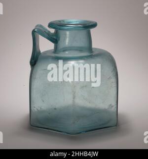 Flacon hexagonal en verre à une poignée fin 1st–début 3rd Century A.D. Roman bleu clair translucide avec teinte verdâtre ; manche de la même couleur. Rebord épais, partiellement tubulaire, plié, vers le bas, rond,et dans ; col cylindrique, évasé vers le bas, avec profil légèrement convexe ; épaulement horizontal, légèrement poussé vers le centre et épaules arrondies inclinées ; corps hexagonal, côtés plats et verticaux ; fond légèrement concave ;main à large bande, épédée sur la surface extérieure, fixée au bord de l'épaule au-dessus d'un côté, tracée verticalement, puis tournée à une poignée aiguë, et traîné sur le cou, avec t Banque D'Images
