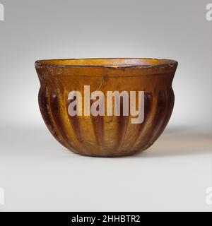 Bol en verre nervuré fin du 1st siècle C.-B.–mi-1st siècle A.D. Roman brun miel translucide.bordure légèrement écartée avec bord supérieur presque pointu et bande lisse à inclinaison vers l'intérieur en dessous, côté convexe profond se courrant vers le fond légèrement concave.à l'intérieur, une seule rainure horizontale large et profonde sous le bord, et une bande de trois (?)Rainures étroites et étroites, peu profondes autour du milieu du corps ; sur l'extérieur, dix-sept longues nervures verticales avec des sommets aplatis, en dépouille vers le bas et s'étendant jusqu'au bord du fond. Cassées et réparées avec de nombreuses fissures et une puce manquante sur le bord ; de nombreuses bulles d'épingle ; dullin Banque D'Images