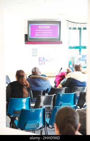 Diverses personnes assises dans une salle d'attente de chirurgie de médecins, attendant d'être vu par un docteur ou une infirmière dans une situation occupée Banque D'Images