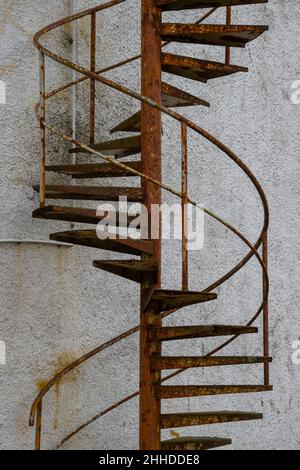 Vieux escalier en colimaçon rouillé menant à une porte fermée à l'extérieur d'un vieux bâtiment Banque D'Images