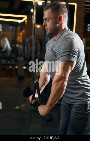 Sportsman s'entraîner sur la machine à câble à la salle de gym Banque D'Images