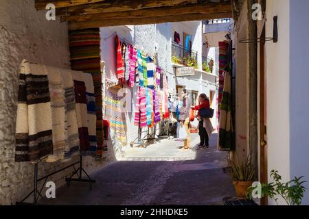 Vue sur une rue de Pampaneira, pleine de tapis, serviettes et couvertures d'artisanat local.Pampaneira, Andalousie, Espagne Banque D'Images