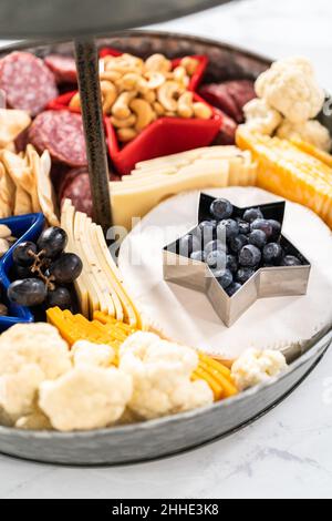 Le 4 juillet, un plateau de charcuterie est servi sur un support métallique à deux niveaux rempli de fromage, de craquelins, de salami et de fruits frais Banque D'Images