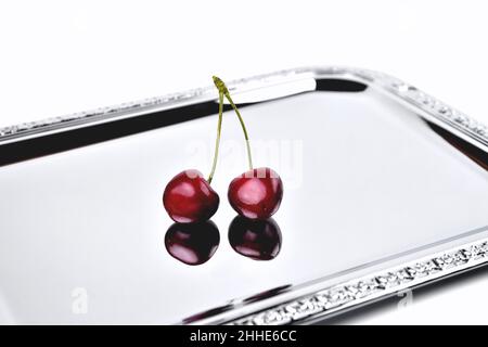 deux cerises mûres sur une surface miroir, gros plan sélectif Banque D'Images