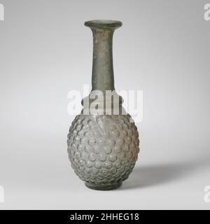 Bouteille en verre en forme de botte de raisin 3rd Century A.D. Roman bleu translucide vert.Rim plié, rond, et dedans, et pressée dans la bouche torchère; col cylindrique se développant vers le bas, avec un léger retrait horizontal d'outils autour de la base; épaule inclinée vers le bas et vers l'extérieur, avec rouleau de projection creux en dessous; corps ovoïde;base cylindrique basse, avec fond concave.Cicatrice Pontil au centre du fond.Corps soufflé dans un moule en trois parties de deux sections verticales, s'étendant de la base au sommet du corps, et une section de base en forme de disque.sur le corps, un modèle de raisins stylisés comprenant onze rangées de tw imbriquées Banque D'Images