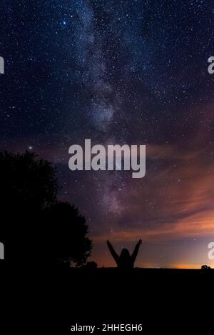 Plan vertical des silhouettes d'une personne pointant vers le la voie lactée dans le ciel nocturne Banque D'Images