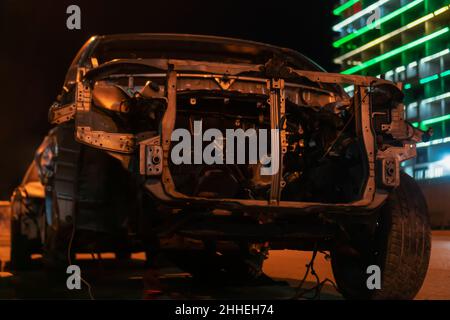 Voiture grise bosselée et cassée sur la route de la ville la nuit Banque D'Images