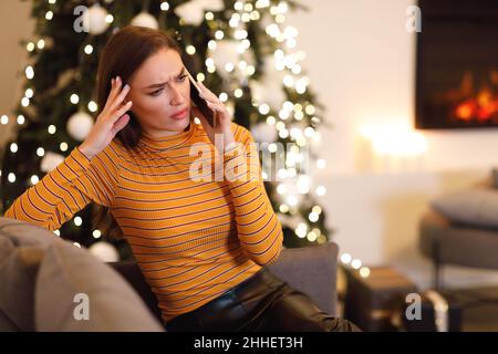 Une dame confuse parlant sur un téléphone portable assis sur un canapé Banque D'Images