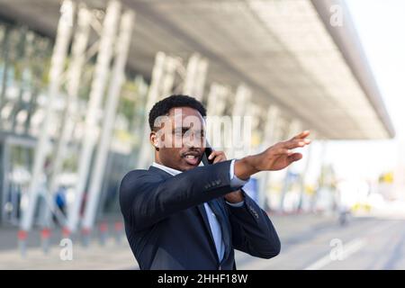 Homme afro-américain parlant sur un téléphone portable près de l'aéroport, homme d'affaires est arrivé lors d'un voyage d'affaires Banque D'Images