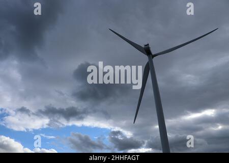 Éolienne contre un ciel sombre et nuageux avec une zone de vue bleue à angle bas Banque D'Images