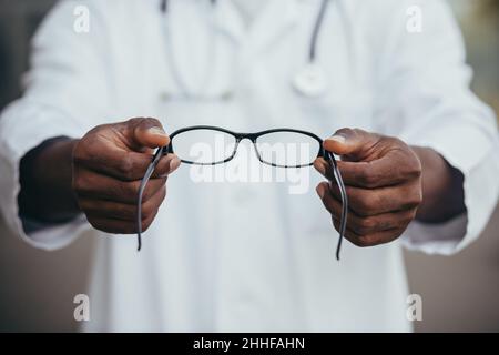 Gros plan Afro-américain médecin offre des lunettes au patient, ophtalmologiste vend des lunettes en magasin Banque D'Images