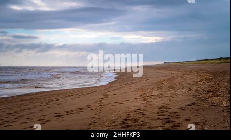 Gros plan de empreintes d'animaux dans le sable sur la plage d'Anderby Creek, Lincolnshire avec une vue sur le village et quelques personnes méconnaissables Banque D'Images