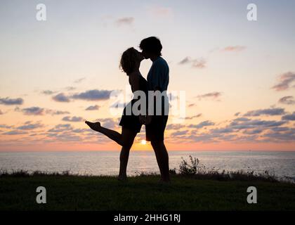 silhouettes pleine longueur d'un jeune couple amoureux, un gars et une fille embrassent sur fond de mer et de coucher de soleil. plaisir du moment, fe tendre Banque D'Images