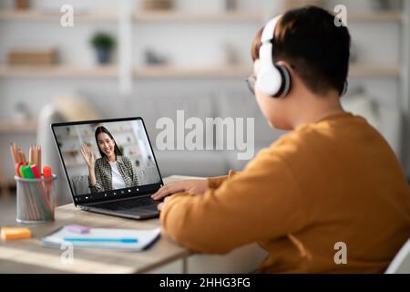 Garçon ayant une vidéoconférence avec un professeur, utilisant un casque et un ordinateur portable Banque D'Images