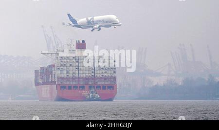 Hambourg, Allemagne.24th janvier 2022.Un avion de transport Airbus de type Beluga survole un énorme navire à conteneurs de la compagnie maritime Hamburg Süd sur l'Elbe à l'approche du site de l'usine de Finkenwerder.L'Elbe est tout à fait clair pour les nouveaux brouillons après l'approfondissement récent du canal de navigation.Credit: Marcus Brandt/dpa/Alay Live News Banque D'Images