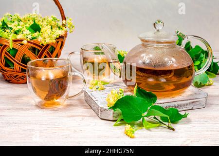 Théière et deux tasses de thé avec un tilleul sur une table en bois. Thé de guérison. Banque D'Images