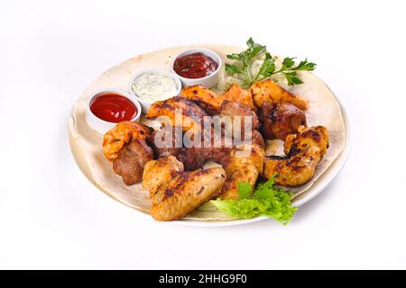 assortiment de viande sur pain pita avec légumes et sauces sur une plaque blanche sur fond blanc isolé. Banque D'Images