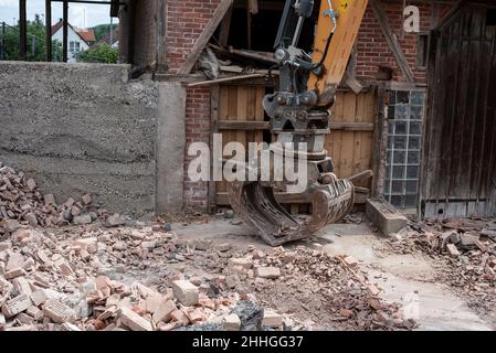 un chantier de construction avec des briques cassées sur le sol et le grand seau en métal d'un creuseur Banque D'Images