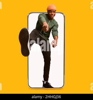 Gai jeune élégant attrayant afro-américain gars pointant les doigts vers l'appareil photo sur grand téléphone écran vide Banque D'Images