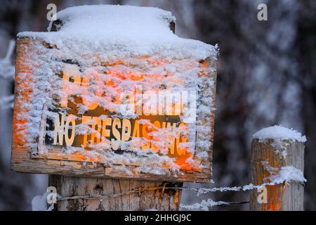 Aucun panneau d'intrusion n'est affiché sur un poteau de clôture en bois en hiver avec un avertissement d'avertissement de neige orange Banque D'Images