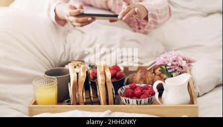 Pour tous les amateurs de cuisine.Photo courte d'une femme prenant une photo de son petit déjeuner au lit à la maison. Banque D'Images