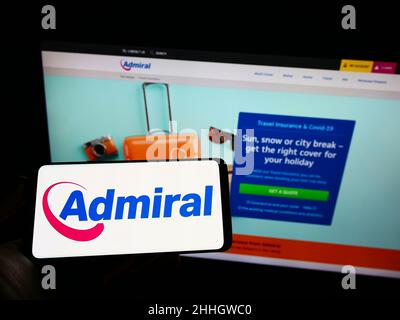 Personne tenant un téléphone portable avec le logo de la compagnie d'assurance britannique EUI Limited (Admiral) à l'écran en face de la page Web.Mise au point sur l'affichage du téléphone. Banque D'Images