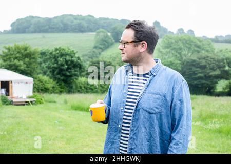 Homme avec une tasse debout dans le champ Banque D'Images