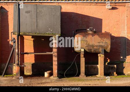 Station de remplissage de carburant et réservoir d'huile de la ferme. Un rectangulaire et un cylindrique contre un mur de grange avec de lourdes ombres graphiques Banque D'Images