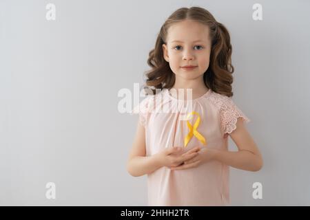 Journée mondiale du cancer de l'enfance.Fille avec ruban doré. Banque D'Images