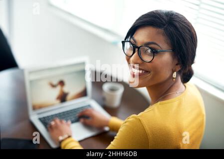 Faire le travail.Prise de vue rognée d'une jeune femme attrayante assise seule à la maison et utilisant son ordinateur portable. Banque D'Images
