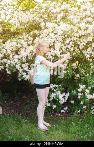 Belle adolescente blonde fille faire selfie sur fleur printemps magnolia arbres fond avec des fleurs blanches parfumées Banque D'Images