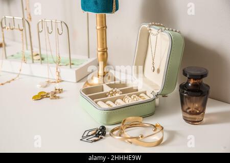 Boîte avec différents bijoux stylés sur une table blanche près du mur lumineux Banque D'Images