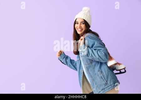 Bonne femme en vêtements d'hiver et avec patins à glace sur fond de couleur Banque D'Images