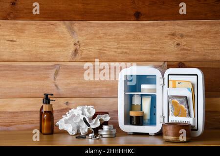 Ouvrez le réfrigérateur cosmétique sur la table près du mur en bois Banque D'Images