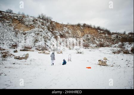 Jeux en famille et promenades en traîneau en hiver en plein air, la mère et les enfants s'amusent. Banque D'Images