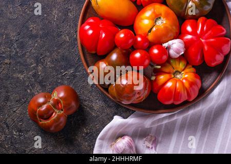 La récolte de tomates assorties.Tomates biologiques colorées sur un grand plat.Tomates différentes variétés.Vue de dessus Banque D'Images
