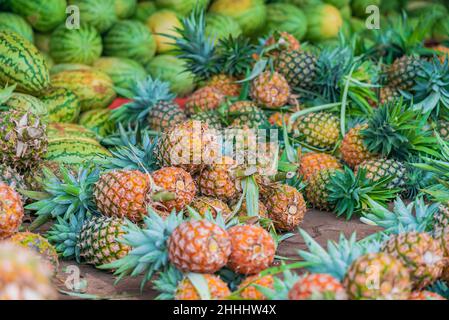 Beaucoup d'ananas et d'eau fondent sur le sol sur le marché alimentaire de Zanzibar, en Tanzanie Banque D'Images