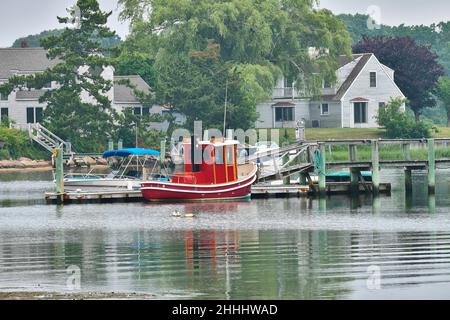 Un joli petit bateau rouge à un quai ou un quai sur Lewis Bay Inlet à Cape Cod, Massachusetts.USA, un jour gris.Près du port de Hyannis. Banque D'Images