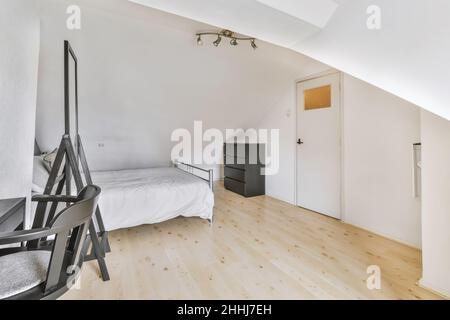 Une chambre moderne et lumineuse avec un lit double, un grand miroir et des meubles gris Banque D'Images