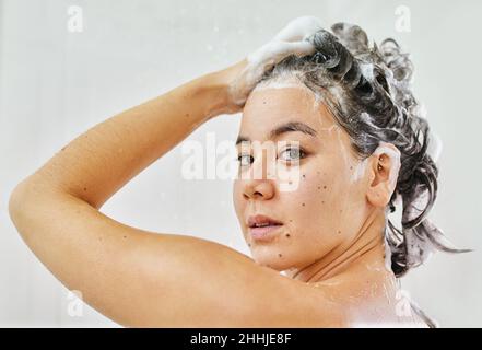 Elle se nettoie parfaitement.Photo d'une jeune femme lavant ses cheveux avec du shampooing dans la douche à la maison. Banque D'Images