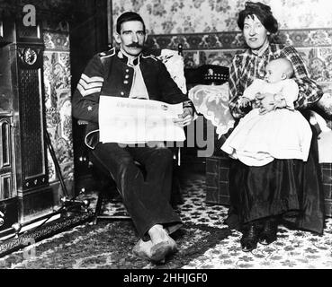 Couleur Sergent Chick de la Garde des Écossais qui a été tiré à la jambe pendant le siège de la rue Sidney, vu ici, à la maison avec sa femme et son enfant.3rd janvier 1911 Banque D'Images