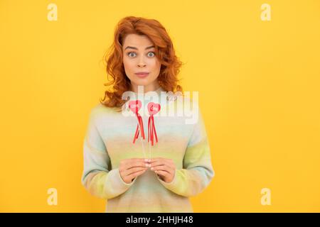 femme surprise redhead avec coeur rouge bâtons sur fond jaune. amour Banque D'Images