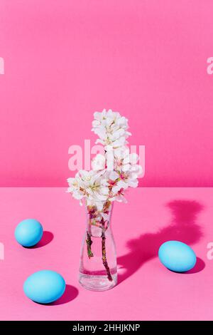 Fleurs d'amande dans un vase transparent avec de l'eau et trois œufs bleus Banque D'Images