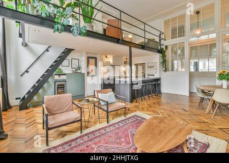 Intérieur ouvert de la salle de séjour avec meubles en bois et moquette près de la maison bar contre l'escalier dans la maison de luxe spacieuse Banque D'Images